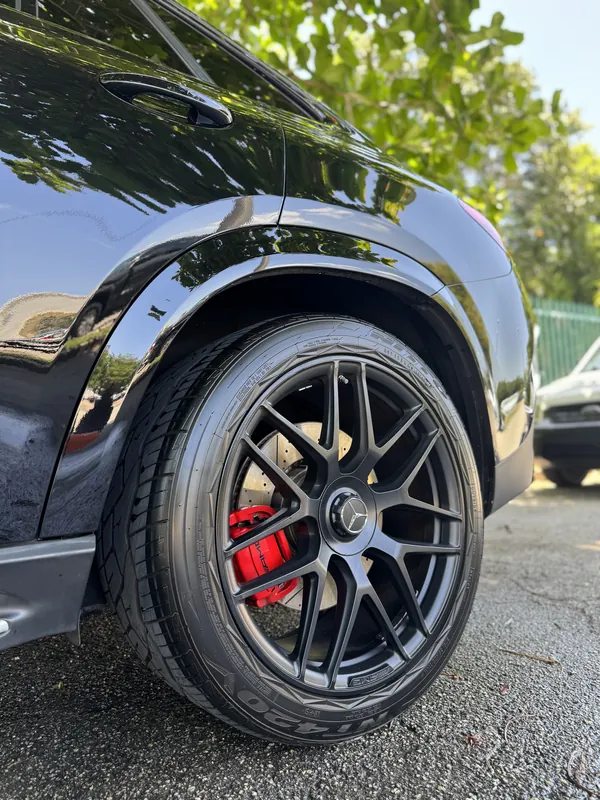 Close-up of a deep-cleaned black wheel and red brake caliper after wheel detailing